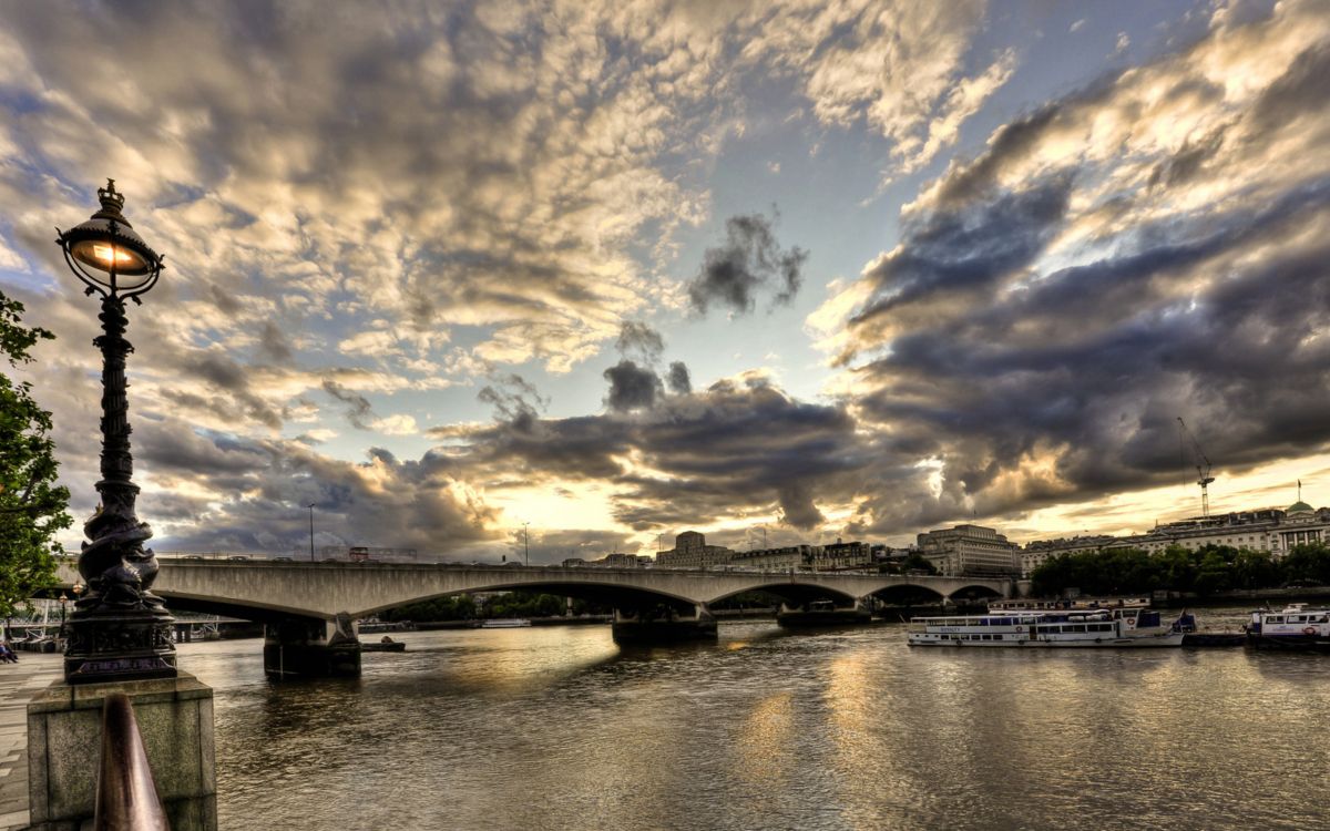 gray concrete bridge over river under blue sky and white clouds during daytime