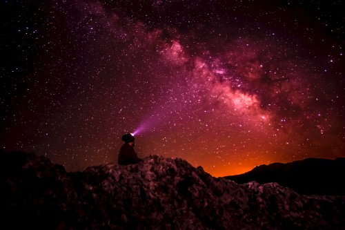 Image man sitting on rock under starry night