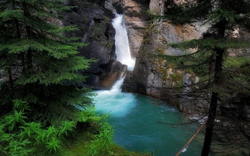 Image waterfalls between brown rocky mountain during daytime