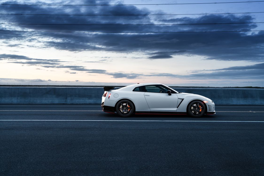 white porsche 911 on road under cloudy sky during daytime