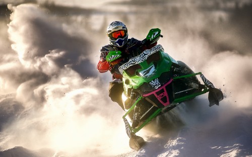 Image man in green and black suit riding green and black snow mobile