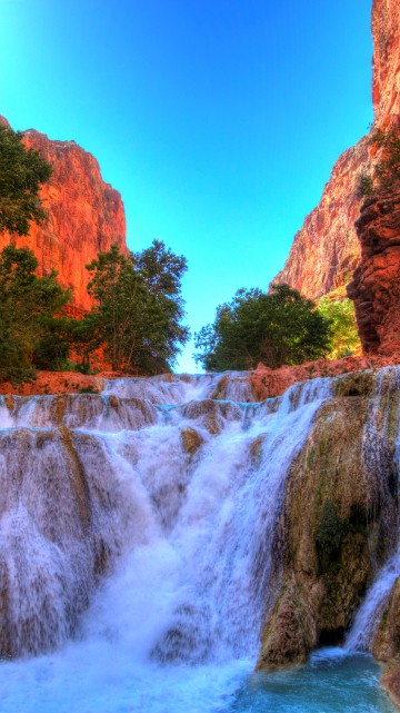 Image waterfalls between brown rocky mountain under blue sky during daytime