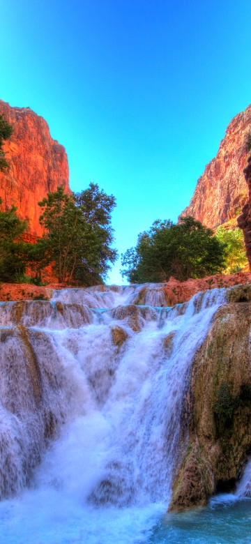 Image waterfalls between brown rocky mountain under blue sky during daytime