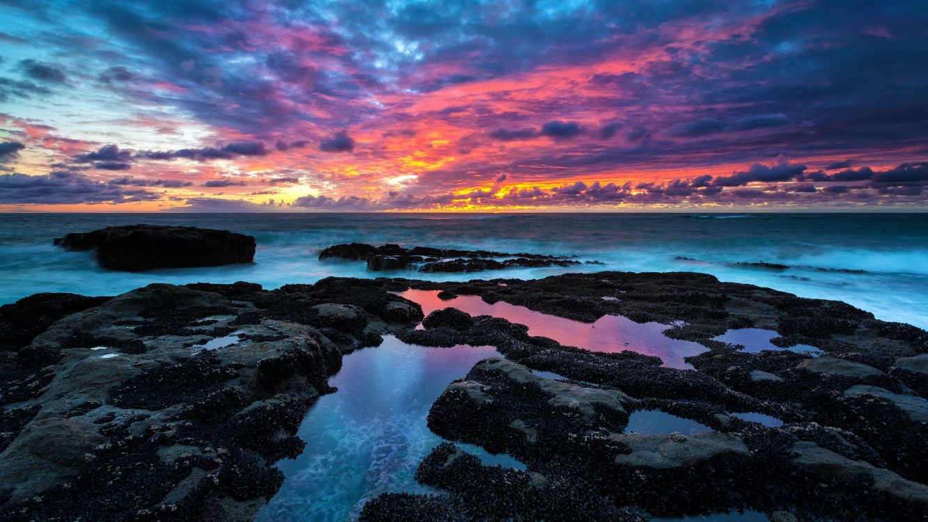 brown rocks on sea shore during sunset