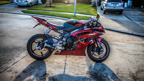 Image red and black sports bike parked on gray concrete pavement during daytime