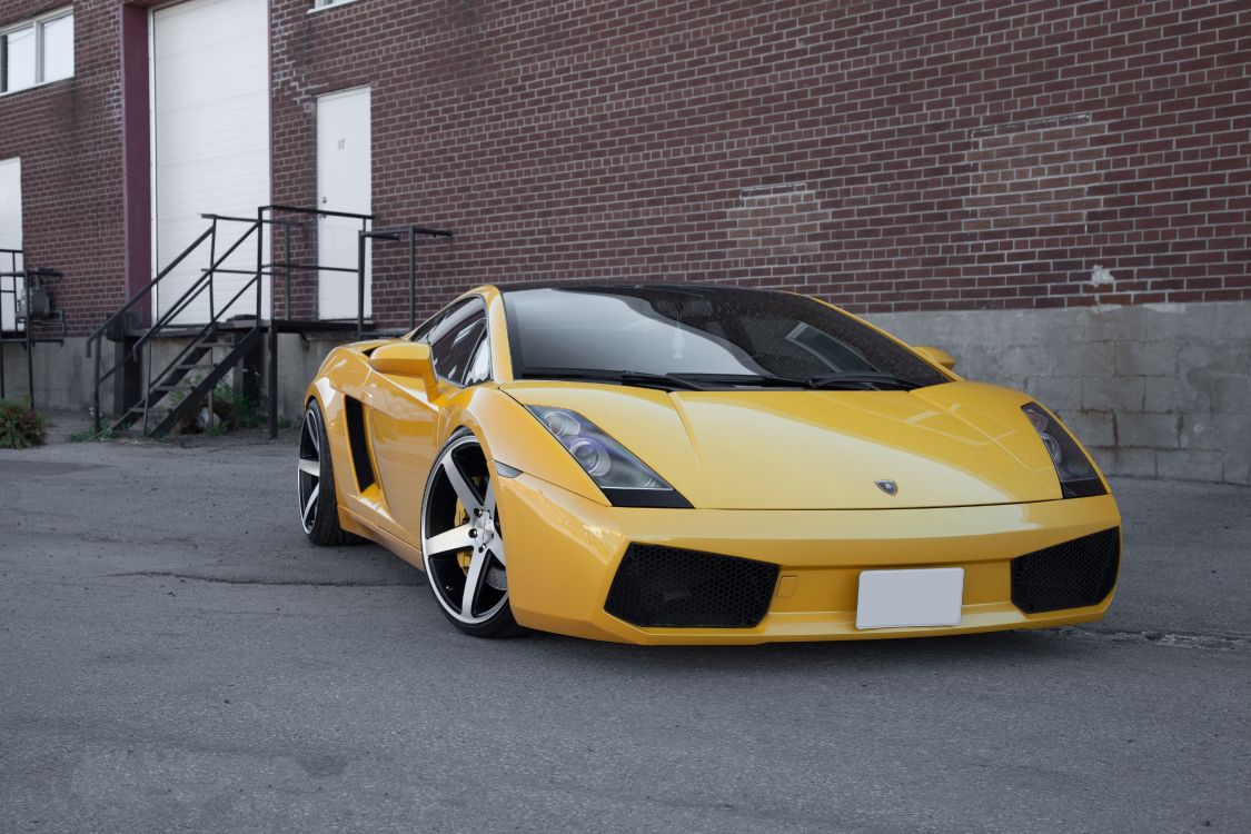 yellow ferrari 458 italia parked near brown brick building