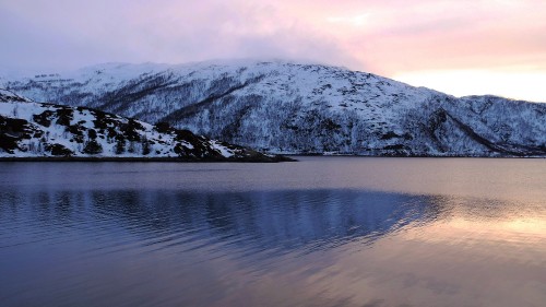 Image snow covered mountain near body of water during daytime