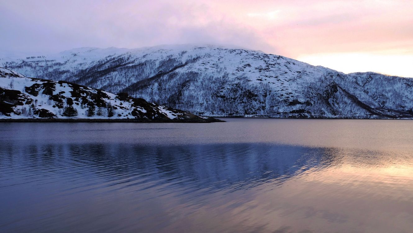 snow covered mountain near body of water during daytime