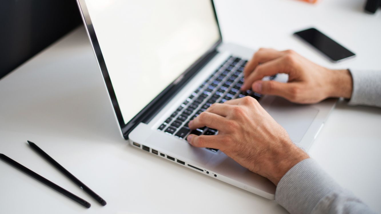 person using macbook pro on white table