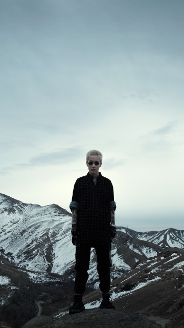 Image man in black jacket standing on rock formation during daytime
