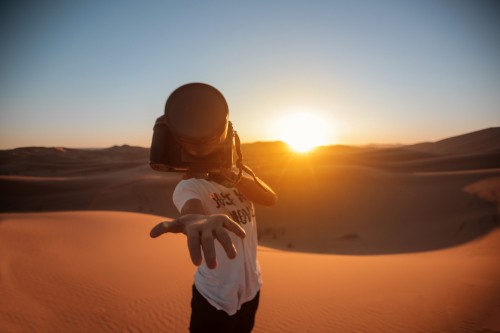 Image man in white shirt and black pants standing on sand during sunset