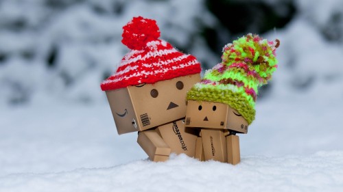 Image brown cardboard box with red and green ribbon on white snow