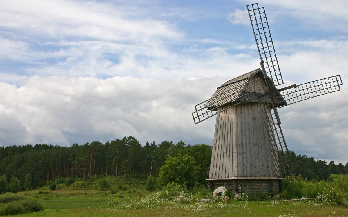 brown wooden house on green grass field under white clouds during daytime