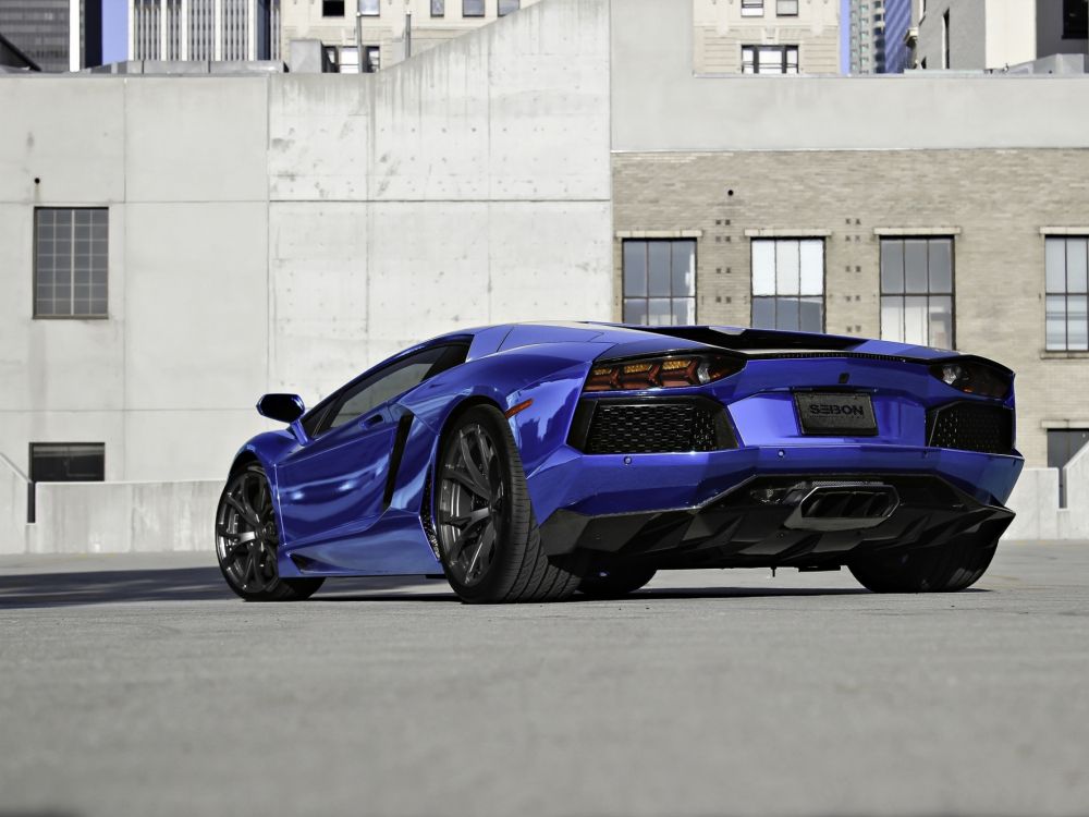 blue lamborghini aventador parked beside white concrete wall
