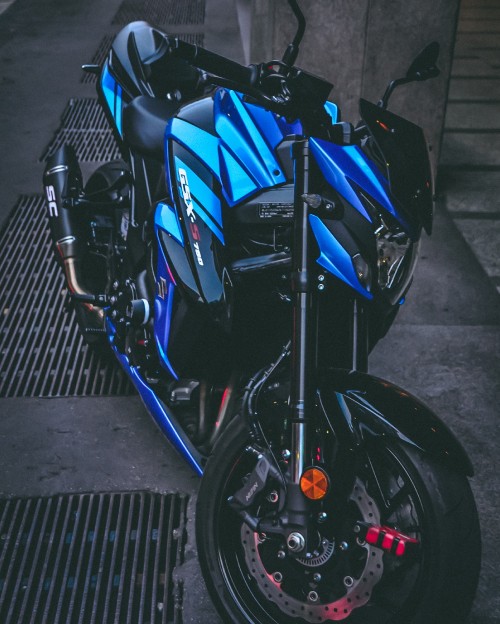 Image blue and black motorcycle parked on gray concrete pavement