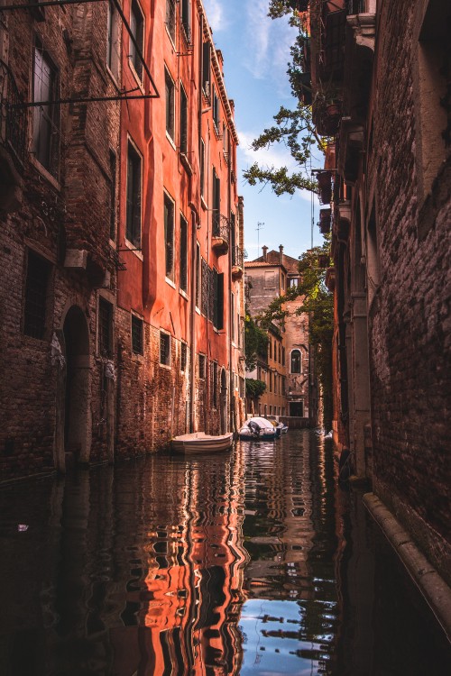 Image boat on river between buildings during daytime