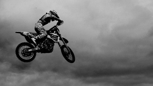 Image grayscale photo of man riding motocross dirt bike