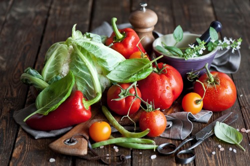 Image red tomato and green leaves on brown wooden chopping board