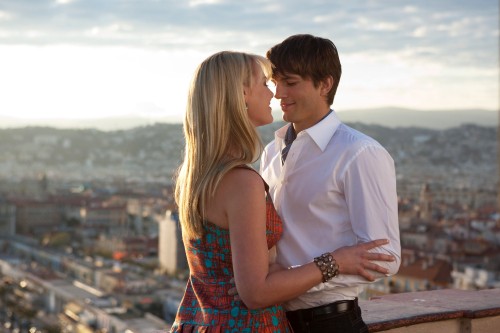 Image man in white suit kissing woman in red and blue sleeveless dress