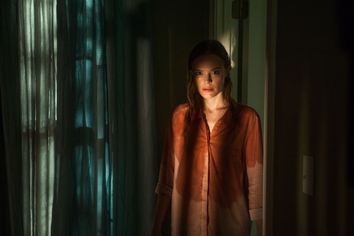 woman in brown robe standing near blue curtain