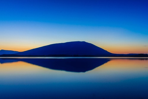 Image body of water near mountain under blue sky during daytime