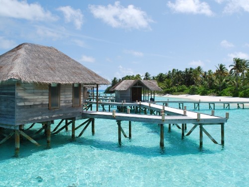 Image brown wooden house on blue sea under blue sky during daytime