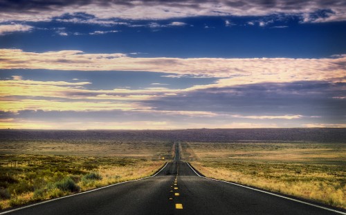 Image black asphalt road between green grass field under blue and white sunny cloudy sky during daytime