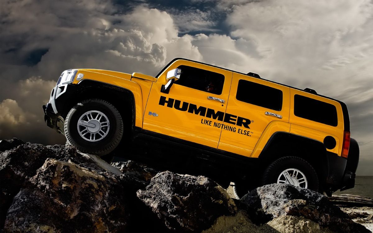 yellow chevrolet crew cab truck on rocky shore under cloudy sky during daytime