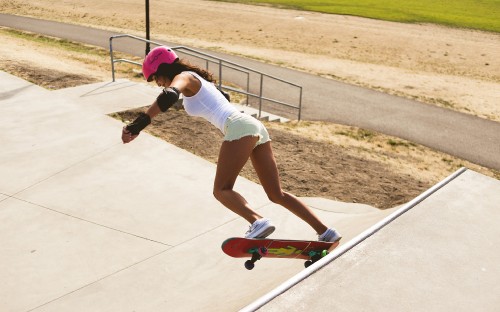 Image woman in white tank top and white shorts riding on skateboard during daytime