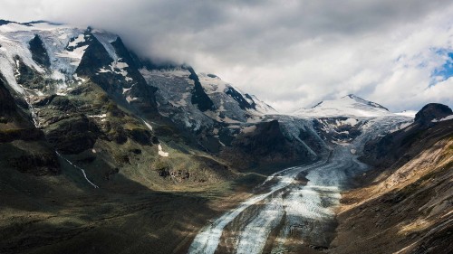 Image snow covered mountains under cloudy sky during daytime