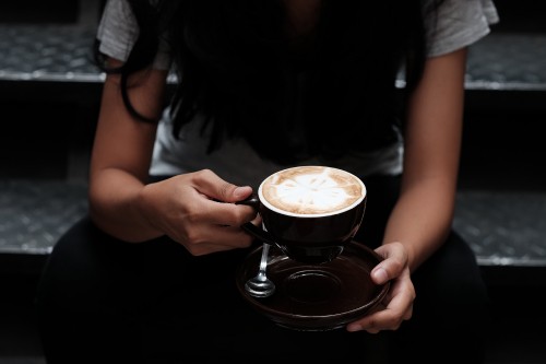 Image woman in black shirt holding cup of coffee