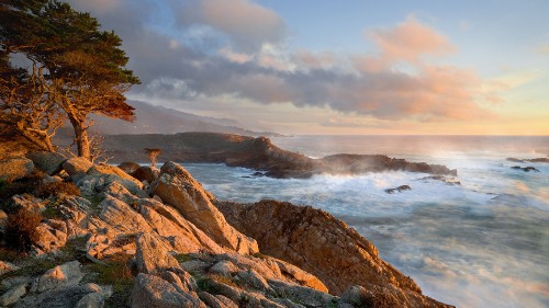 Image person sitting on brown rock formation near body of water during daytime