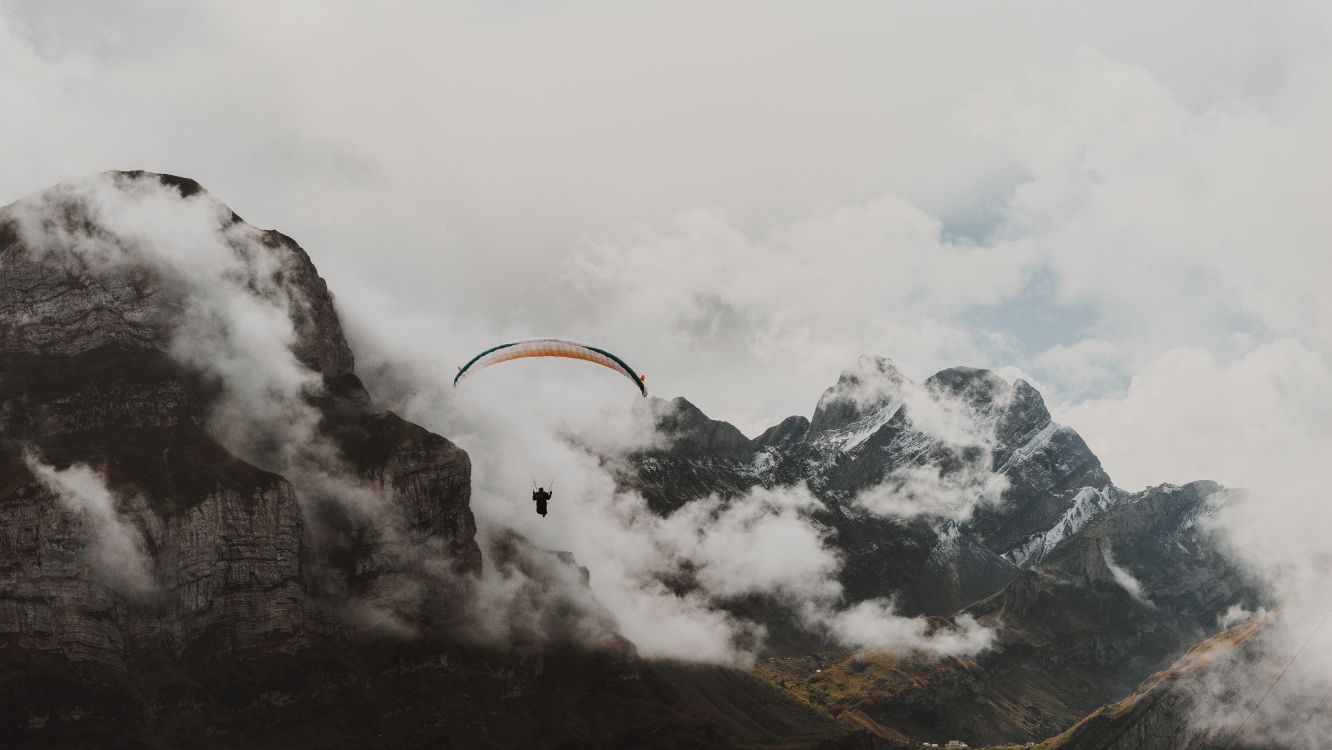 Person Reitet Fallschirm Über Schneebedeckten Berg. Wallpaper in 6000x3376 Resolution