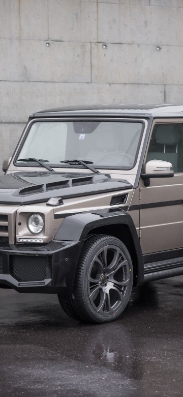 Image brown and black suv parked beside white wall