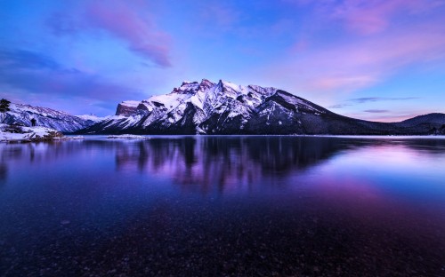 Image snow covered mountain near lake under blue sky during daytime