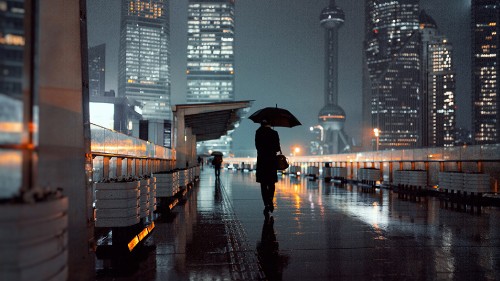 Image person in black jacket and black pants holding umbrella walking on sidewalk during night time