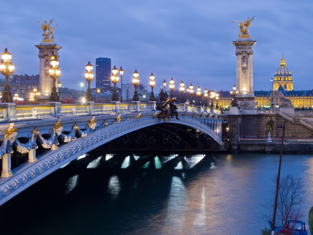 bridge over water near city buildings during night time