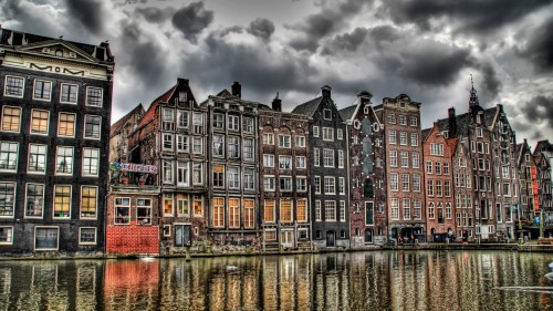 Image brown and black concrete building near body of water under gray clouds