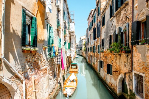 Image boat on river between buildings during daytime