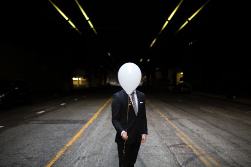 Image man in black coat and pants standing on road during night time