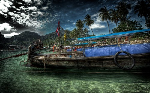 Image brown wooden boat on water near mountain under cloudy sky during daytime