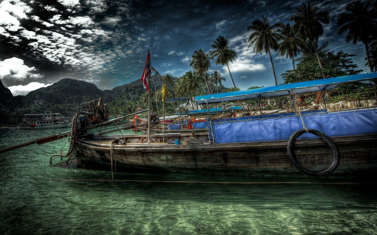 brown wooden boat on water near mountain under cloudy sky during daytime