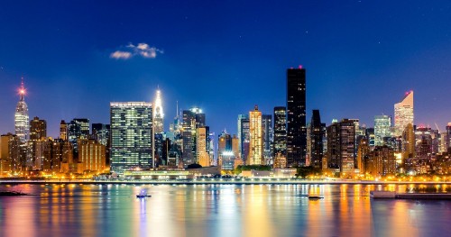 Image city skyline across body of water during night time