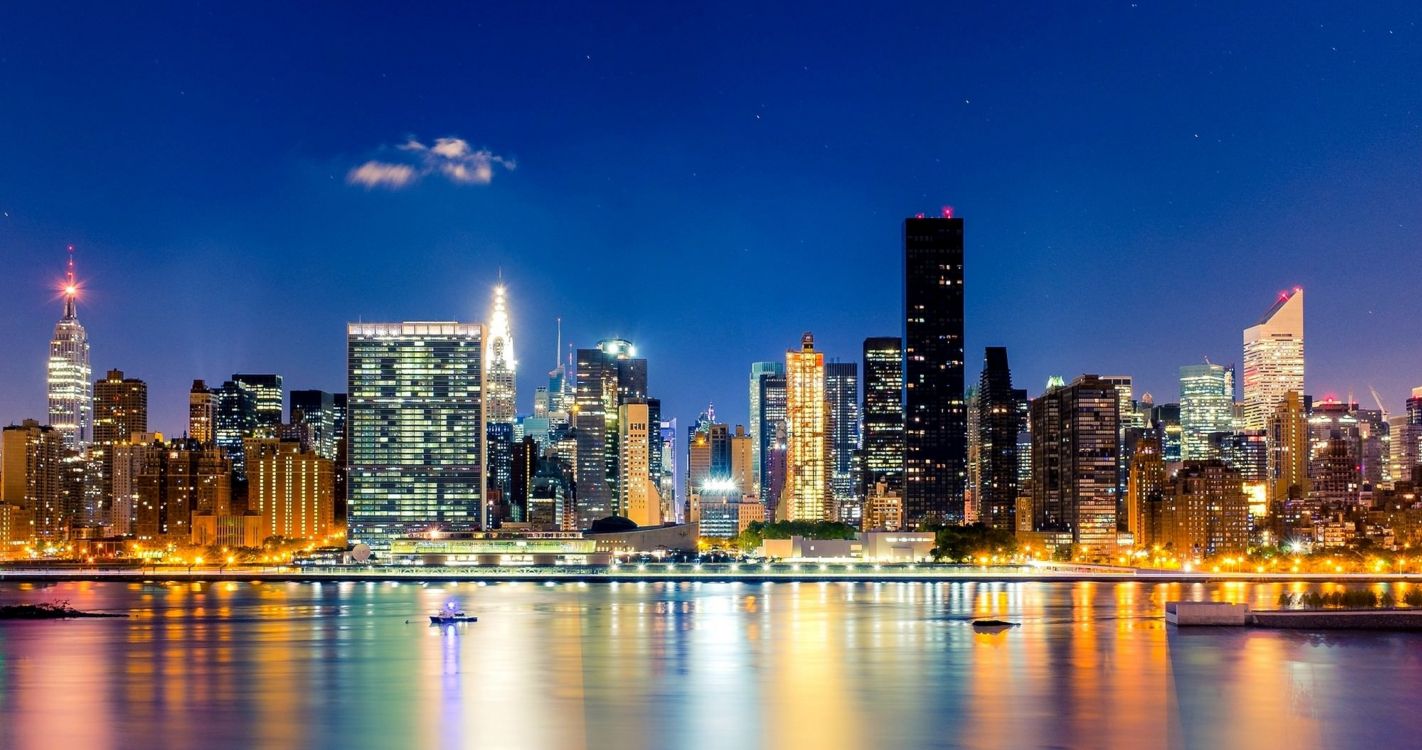 city skyline across body of water during night time