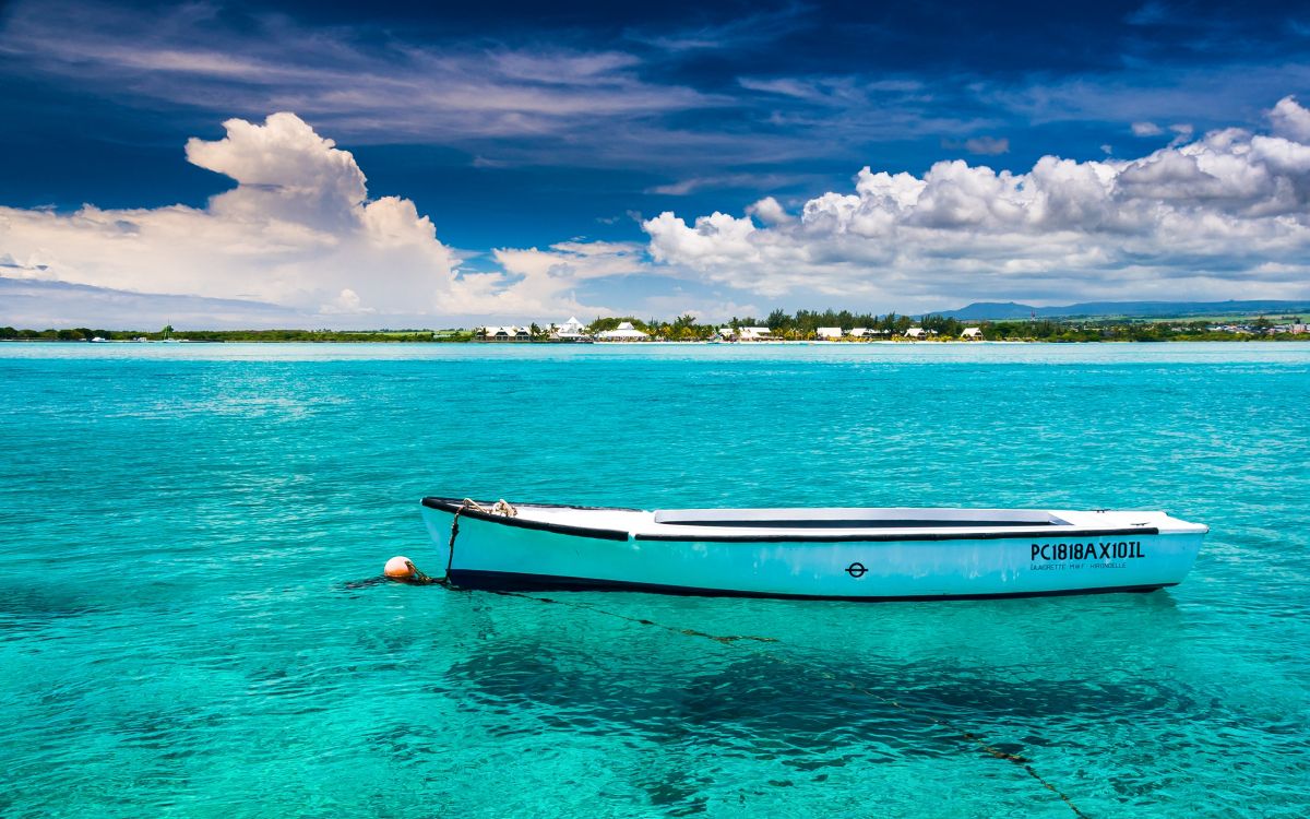 white and brown boat on blue sea under blue and white cloudy sky during daytime