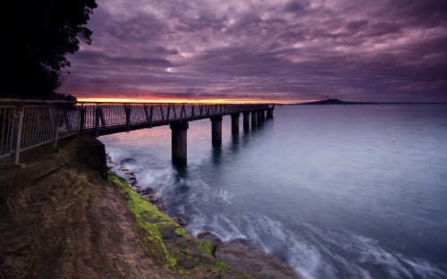 Image brown wooden bridge over the sea under gray clouds