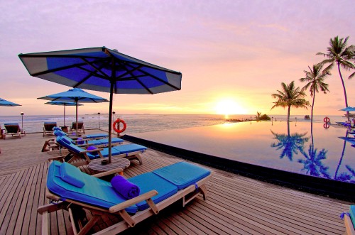 Image blue and white lounge chairs on beach during sunset