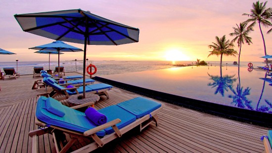 Image blue and white lounge chairs on beach during sunset