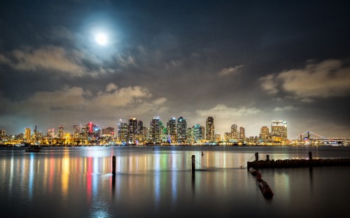 Image city skyline across body of water during night time