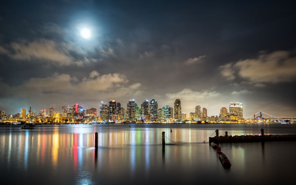 city skyline across body of water during night time